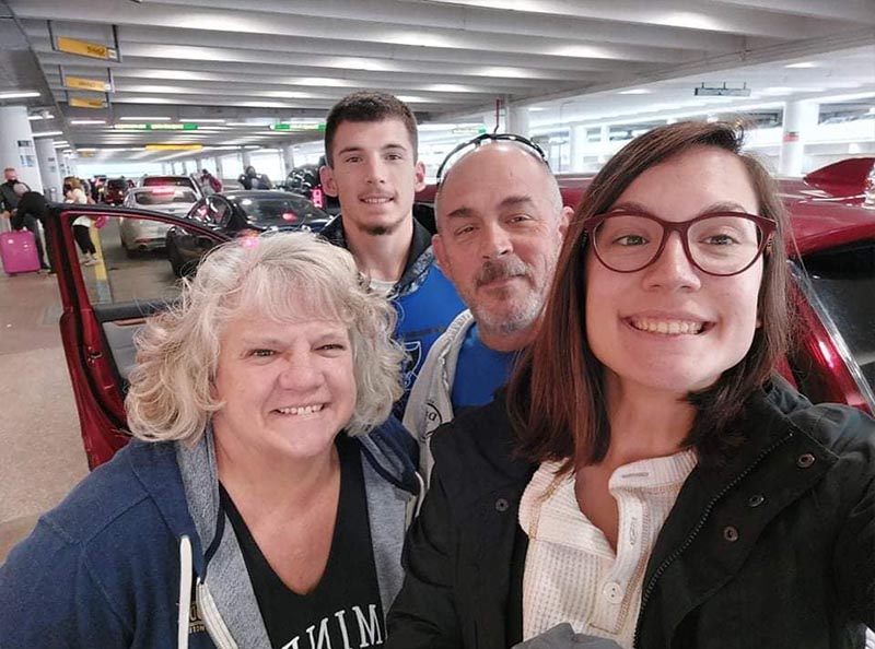 Susan - Smiling with Family While Getting Out of a Car at an Airport