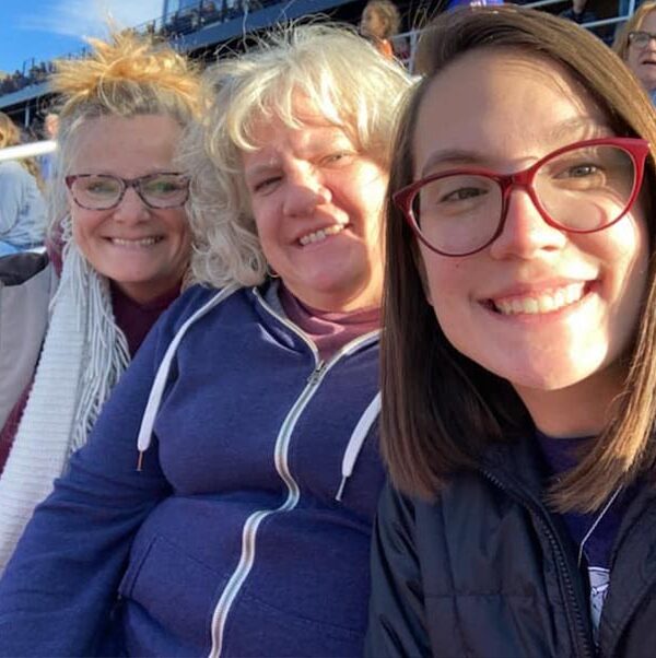 Susan - Susan Smiling with Two Girls While Sitting in the Stands with People Around Them